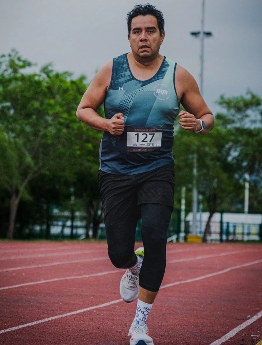 Alex, papá deportista, corriendo con dorsal 127 en una pista de atletismo