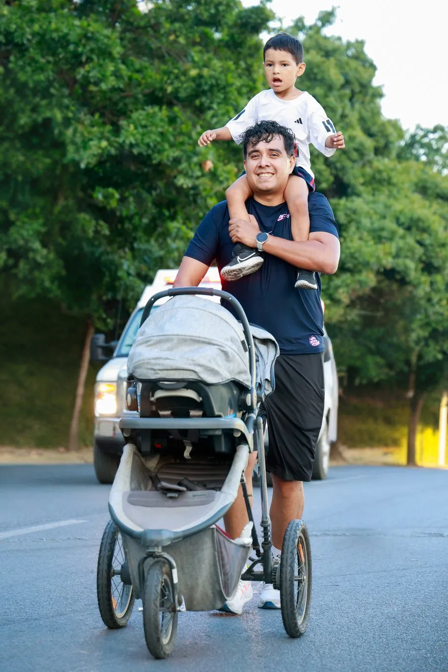 Papá corriendo con carriola en Monterrey mientras su hijo va sobre sus hombros