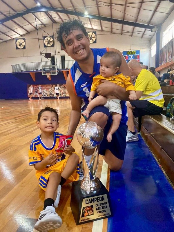 Campeones de basquetbol con el trofeo, en familia